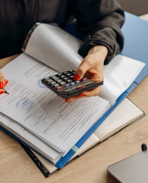 Person using calculator and documents for accounting tasks in an office setting.